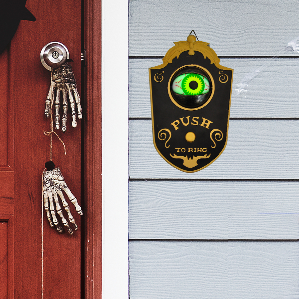 Kapı yanında asılı Halloween kapı zilinin kapağı açık ve yeşil gözü görünür kullanım örneği.