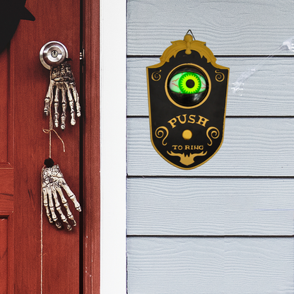 Kapı yanında asılı Halloween kapı zilinin kapağı açık ve yeşil gözü görünür kullanım örneği.